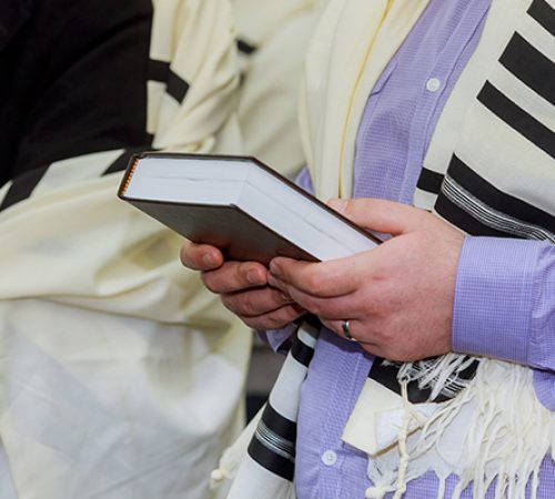 Hands holding a jewish prayer book wearing a prayer shawl Hands holding a jewish prayer book wearing a prayer shawl
